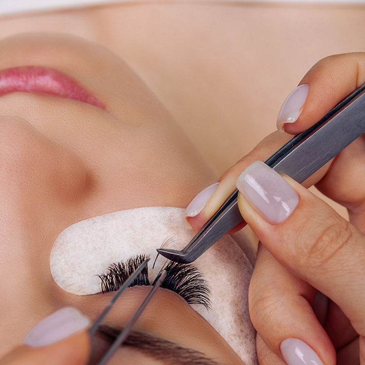 Cliente no Espaço Bela Harmonia recebendo um alongamento de cílios, com um profissional aplicando as extensões para um olhar mais alongado e volumoso.