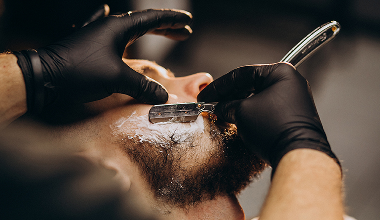 Um homem usa uma navalha para fazer a barba, demonstrando atenção aos detalhes em sua rotina de cuidados pessoais.