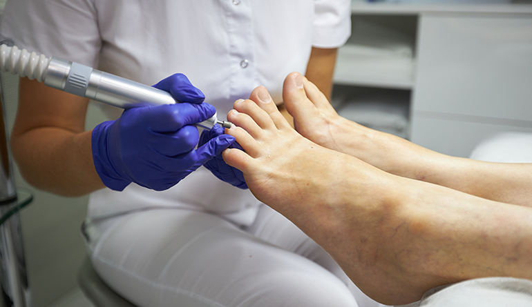 Cliente no Espaço Bela Harmonia desfrutando de um cuidado de pedicure, com o uso de um massageador de pés para um tratamento relaxante.